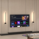Two black wall lights flanking a wall-mounted TV on a wood panel