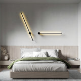 Two angled black wall lights above a bed with a wooden headboard