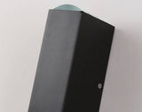 Top corner detail of the matte black aluminium sconce body on a pale wall