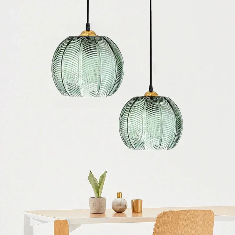 Pair of green glass globe pendant lights with fluted palm leaf texture and wooden tops