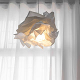 Detail of the folded paper shade glowing behind a sheer white curtain
