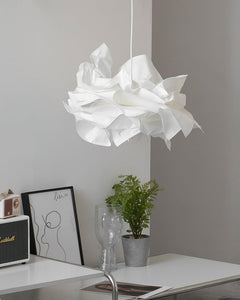 White paper pendant light hanging low over a plain white desk and plant