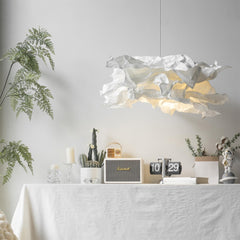 Paper pendant shade lit above a table setting framed by trailing greenery