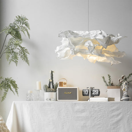Paper pendant shade lit above a table setting framed by trailing greenery