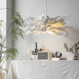 Paper pendant light above a linen covered table with candles and a fern