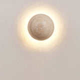 Round travertine wall sconce shown at 5.91 in / 15 cm across