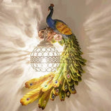 Green and blue peacock wall sconce lit warmly with crystal ball shade at left
