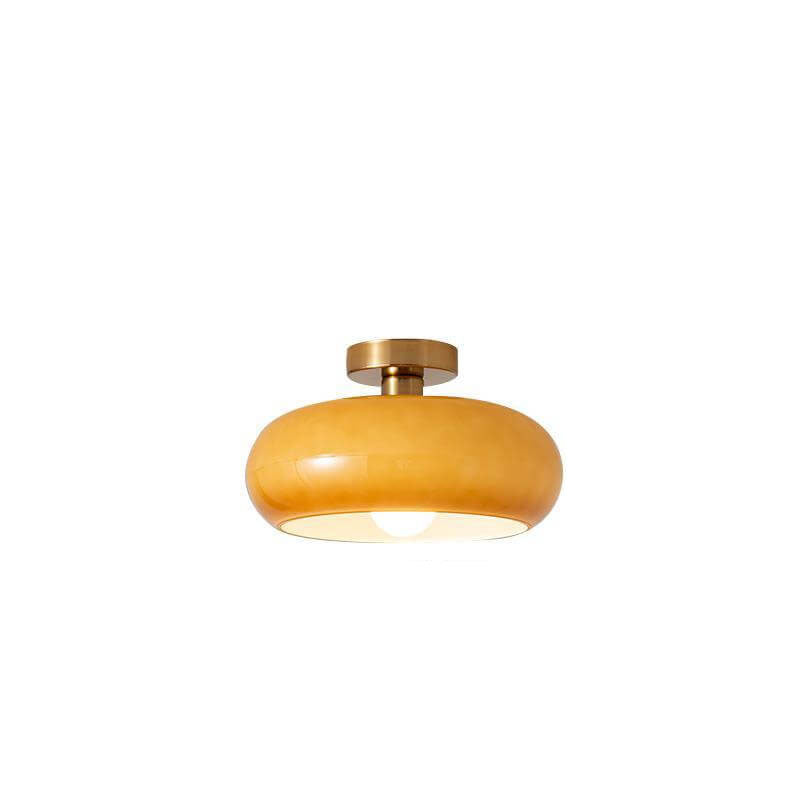Amber orange glass ceiling light shade against a plain studio background