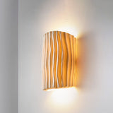 Creamy yellow wall sconce lit with warm up and down ambient light