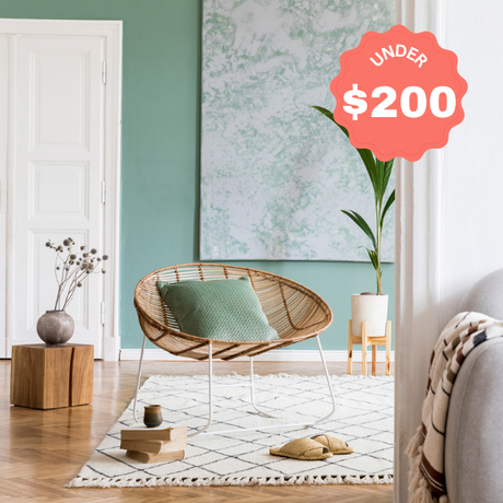 Modern living room with a wicker chair, green cushions, and decorative items on a budget.