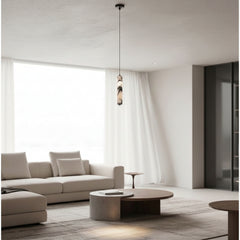 A modern living room featuring a minimalist beige sofa, a round wooden coffee table, and a distinctive pendant light with a textured, layered glass shade hanging from a thin black cord.