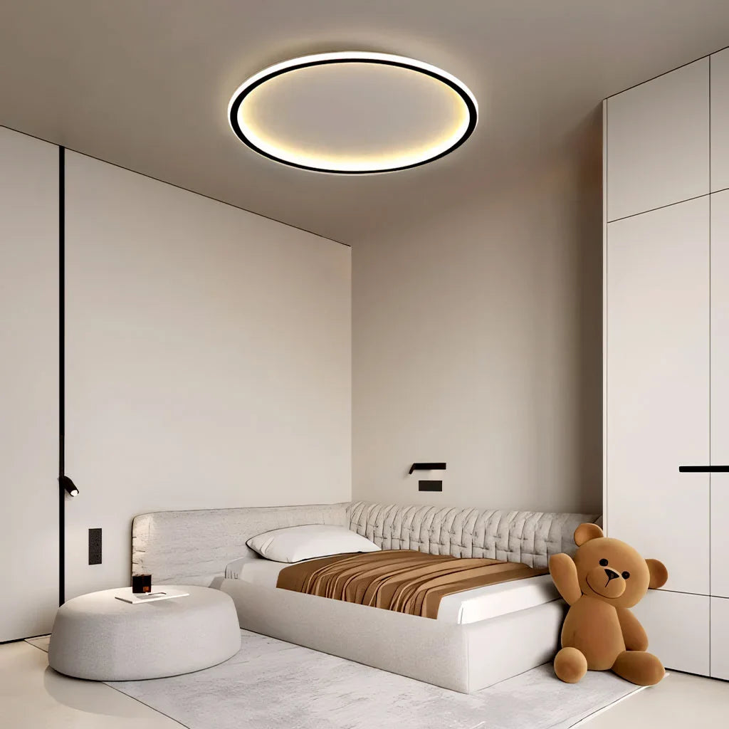 Black round LED ceiling light casting soft light in a bedroom
