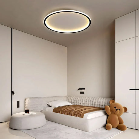 Black round LED ceiling light casting soft light in a bedroom