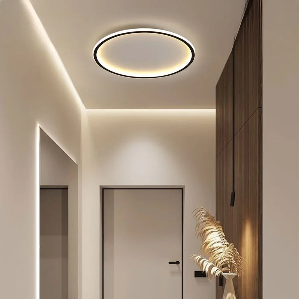 Black round ceiling light lighting a modern corridor with warm glow