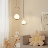 Two gold oval frame glass globe pendants beside a sofa and framed line art