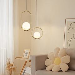 Two gold oval frame glass globe pendants beside a sofa and framed line art