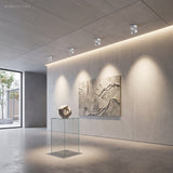 Row of surface mounted spot lights washing a textured stone artwork on a wall