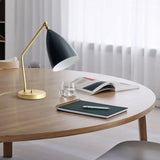 Brass table lamp with adjustable arm on a desk