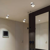 White adjustable spot lights angled along a curved hallway beside a mirror