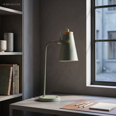 Sage desk task light beside a window and open notebook on a desk