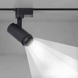 Black tubular track spotlight aimed down casting a focused beam