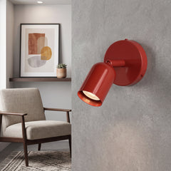 Red adjustable spotlight wall sconce with its head tilted down in a living room