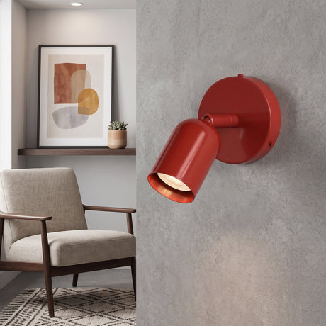 Red adjustable spotlight wall sconce with its head tilted down in a living room