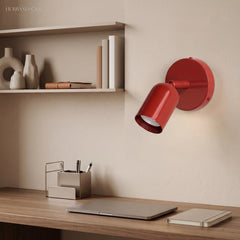 Red spotlight wall sconce aimed at a desk in a home study