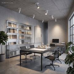 Row of white tube spotlights on a concrete ceiling above a long office table