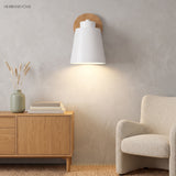 White sconce lit on a plain wall above an oak sideboard