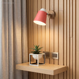Pink sconce lit on slatted timber above a small plant shelf