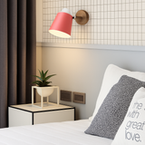 Pink sconce lit on a grid panel above a white bed