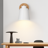 White sconce lit close up against a pale wall above a desk
