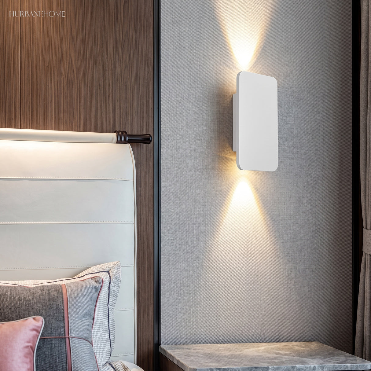 White rectangular wall sconce casting up and down beams in a bedroom