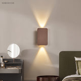 Coffee up and down wall sconce beside a bed and round vanity mirror