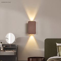 Coffee up and down wall sconce beside a bed and round vanity mirror