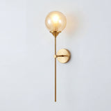 Amber glass globe wall lamp on a slim brass stem