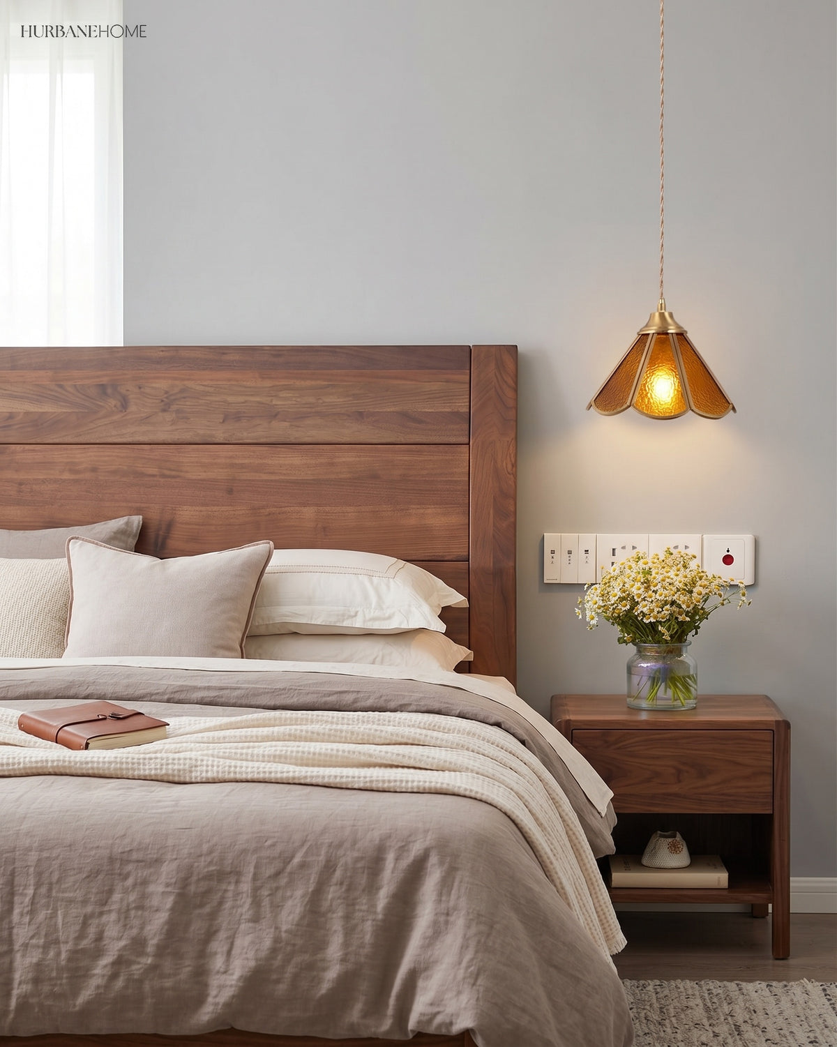 Amber glass pendant lit beside a wooden headboard and a linen made bed