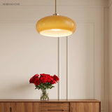 Amber glass pendant hanging on a copper rod above a wooden console with roses