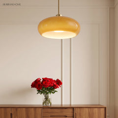 Amber glass pendant hanging on a copper rod above a wooden console with roses