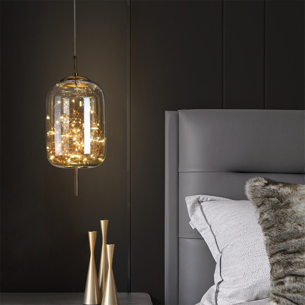 Starry LED pendant in amber glass hanging beside a grey upholstered bed