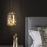 Starry LED pendant in amber glass hanging beside a grey upholstered bed