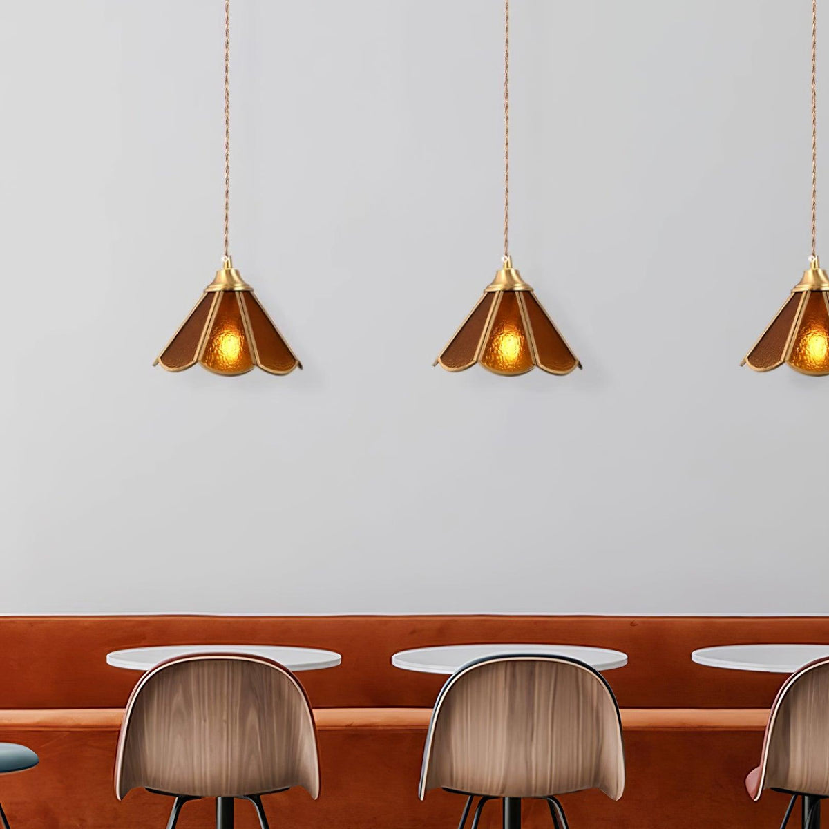 Three amber glass pendants hung in a row above a cafe counter and stools