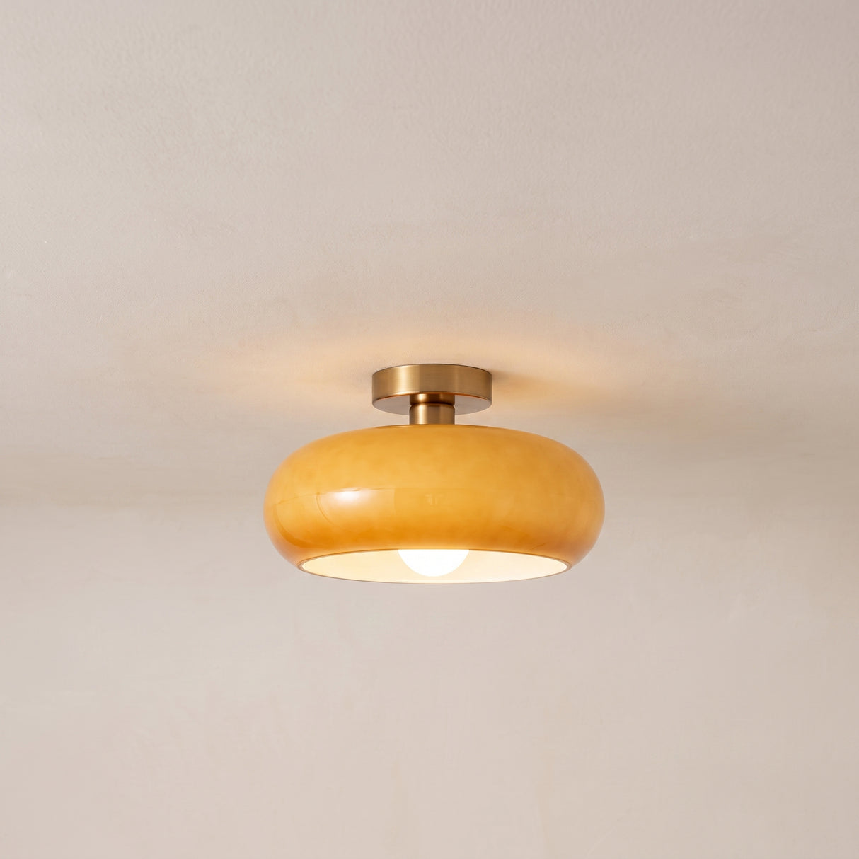Amber glass flush mount ceiling light with copper stem, lit product photo