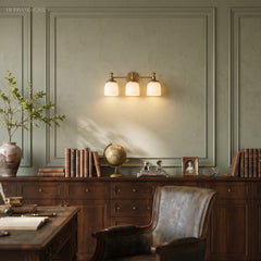 Three light milk glass vanity sconce above a desk in a green study