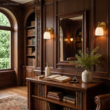 Pair of milk glass sconces in a panelled library with arched windows