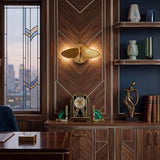 Winged moth wall light above a walnut desk in a city apartment study