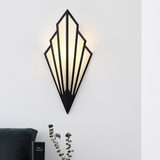 Black fan sconce lit on a white wall above a dark sofa