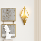 Gold fan sconce lit on a cream wall between two framed pictures