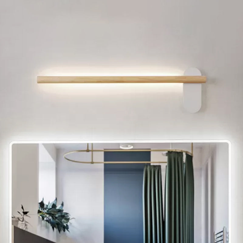 Slim wood vanity light lit above a mirror in a green bathroom